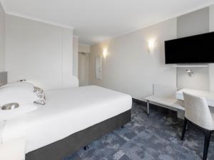 a bedroom with a bed and a desk and a tv at JetPark Auckland Airport Hotel in Auckland