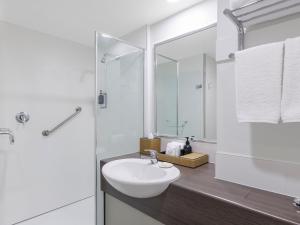 a white bathroom with a sink and a shower at JetPark Auckland Airport Hotel in Auckland