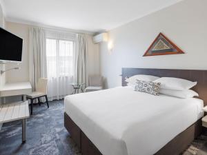 a hotel room with a large bed and a desk at JetPark Auckland Airport Hotel in Auckland