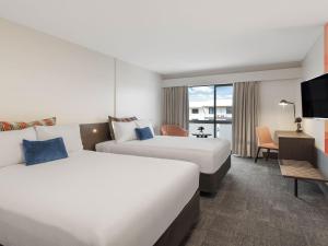 a hotel room with two beds and a tv at JetPark Auckland Airport Hotel in Auckland