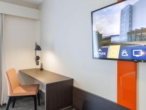 a room with a desk and a tv on a wall at JetPark Auckland Airport Hotel in Auckland