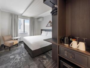 a hotel room with a bed and a chair at JetPark Auckland Airport Hotel in Auckland