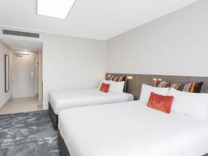 two beds in a hotel room with white at JetPark Auckland Airport Hotel in Auckland