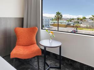 an orange chair sitting next to a window with a table at JetPark Auckland Airport Hotel in Auckland