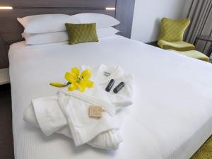 a hotel room with a white bed with towels and a flower on it at JetPark Auckland Airport Hotel in Auckland