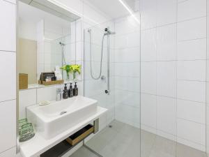a white bathroom with a sink and a shower at JetPark Auckland Airport Hotel in Auckland