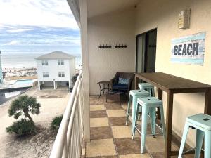 einen Balkon mit Tisch und Stühlen sowie Strand in der Unterkunft Sugar Beach 321 by ALBVR - Beautiful condo at the beach from ALBVR! in Gulf Shores