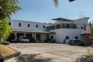 un edificio blanco con coches estacionados en un estacionamiento en Hotel Jorges Morelia, en Morelia