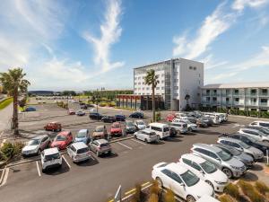 a parking lot with cars parked in front of a building at JetPark Auckland Airport Hotel in Auckland