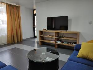 sala de estar con TV y sofá azul en Elegante apartamento con vistas al volcán Tungurahua, en Baños