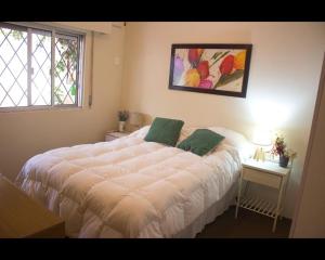 a bedroom with a large white bed with two green pillows at Apartamento independiente en alquiler En casa de familia in Montevideo