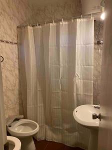 a bathroom with a white shower curtain and a toilet at Apartamento independiente en alquiler En casa de familia in Montevideo