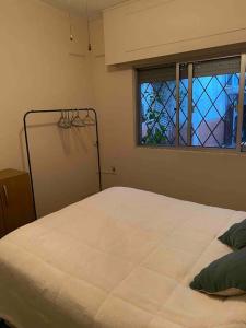 a bedroom with a white bed with a window at Apartamento independiente en alquiler En casa de familia in Montevideo