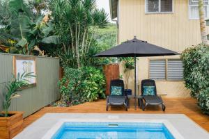 um pátio com duas cadeiras e um guarda-sol ao lado de uma piscina em The Cooks Oasis em Rarotonga
