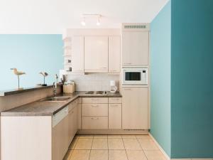 een keuken met witte kasten en een blauwe muur bij Apartment in Koksijde near the Sea in Koksijde