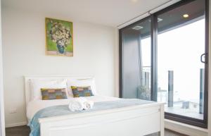a bedroom with a white bed with towels on it at Pinnacle Apartment in Auckland