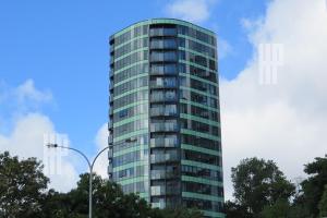 a tall glass building with trees in front of it at Pinnacle Apartment in Auckland