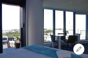 a bedroom with a bed and a table and some windows at Pinnacle Apartment in Auckland