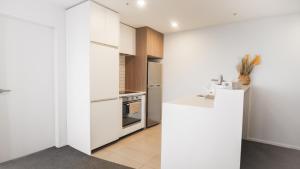 a kitchen with white cabinets and a white counter top at Pinnacle Apartment in Auckland