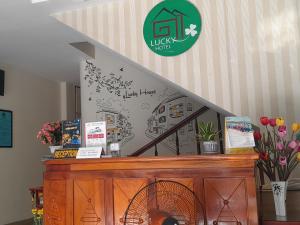 a sign on a wall above a counter with flowers at Lucky Hotel in Hoi An