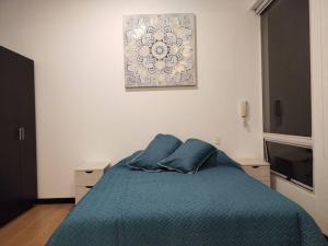 a bedroom with a blue bed with a picture on the wall at Espectacular Dúplex moderno in Bogotá