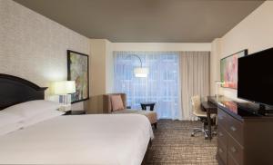 Pokój hotelowy z łóżkiem, biurkiem i telewizorem w obiekcie Houston Marriott Sugar Land w mieście Sugar Land