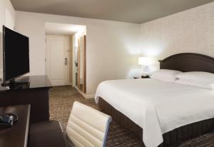 a hotel room with a bed and a flat screen tv at Houston Marriott Sugar Land in Sugar Land