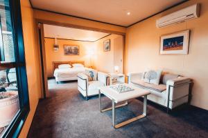 a room with a bed and two chairs and a table at Beach Holiday Apartments in Rye