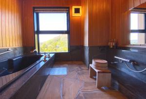 a bathroom with a tub and a toilet and a window at Hotel Gyokusen in Matsue
