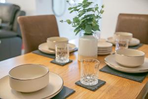 a wooden table with plates and glasses on it at Maidencraig Court House ✪ Grampian Lettings Ltd in Aberdeen