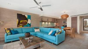 a living room with a blue couch and a table at Penthouse - Palm Cove in Palm Cove