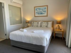 a bedroom with a large white bed with two pillows at The Boathouse Luxury Apartments in Tea Gardens