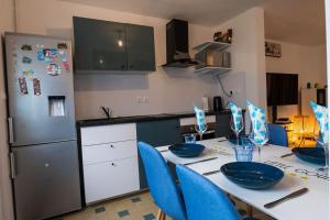 a kitchen with a table with blue chairs and a refrigerator at Maison de ville Rouen Darnétal in Darnétal