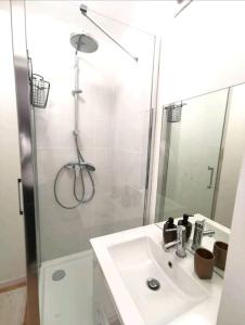 a white bathroom with a sink and a shower at Maison de ville Rouen Darnétal in Darnétal