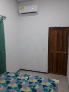 1 dormitorio con 1 cama y puerta de madera en HOSTAL ZAS, en Mompox