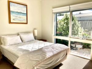 a bedroom with a bed and a large window at Glan Mor in Queenscliff