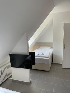 a white room with a bed and a television at Pension Wob in Wolfsburg