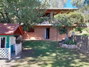 ein Backsteinhaus mit einem Zaun vor einem Hof in der Unterkunft Hermosa casa frente al rio icho cruz 10 personas in Villa Icho Cruz