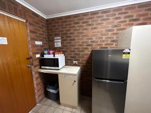 a kitchen with a refrigerator and a microwave on a counter at Balranald Colony Inn Motel in Balranald