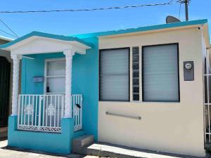 a blue and white house with a white door at Mi casa El Rincón in Juana Diaz