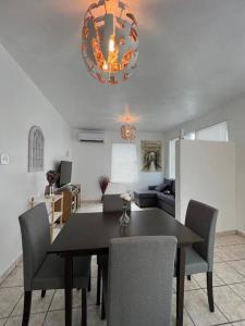 a dining room table with chairs and a chandelier at Mi casa El Rincón in Juana Diaz