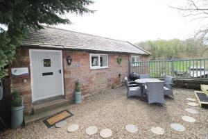 ein kleines Backsteinhaus mit einem Tisch und Stühlen in der Unterkunft Mill House Cottage, Fishing Park, Brampton, Nr Carlisle in Brampton