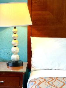 une lampe assise sur une table à côté d'un lit dans l'établissement Relax Inn Lawton, à Lawton