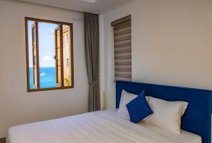 Un dormitorio con una cama azul y blanca y una ventana en Rose Hotel Phú Quốc, en Phu Quoc