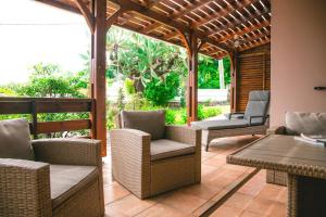 a patio with wicker chairs and a wooden pergola at Villa Le Colonial Zen - T4 à 5 mn Aéroport in Sainte-Marie