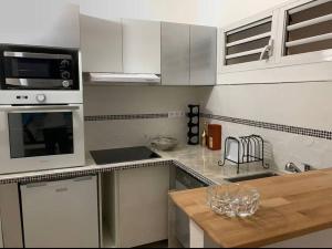 a kitchen with white cabinets and a wooden counter top at Le Lantana by EGL IMMO in Le Marin