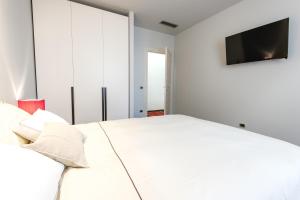a bedroom with a white bed and a flat screen tv at Italianflat - Arena di Verona Apartments in Verona