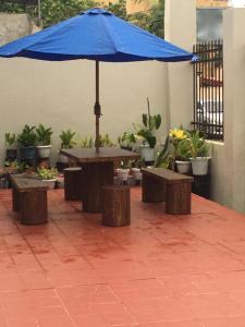 a table with a blue umbrella and some plants at Donadel Hometel in Iloilo City