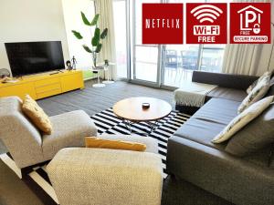 uma sala de estar com um sofá e uma televisão em 2bdrm Skyline Views - Prime for River, WACA, OPTUS Stadium em Perth