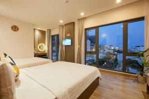 クイニョンにあるLux Quy Nhon Homestayのベッド2台と大きな窓が備わるホテルルームです。